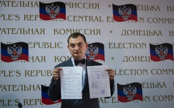 Co-chairman of the Presidium of the People's Republic of Donetsk and vote-counter Roman Lyagin shows documents with the results of the referendum to journalists at a news conference in Donetsk, Ukraine, Monday, May 12, 2014, with Donetsk republic signs in the background. The balloting Sunday in the Donetsk and Luhansk regions_ which together have 6.5 million people _ was condemned as a sham and a violation of international law by Kiev’s interim government and the West. (AP Photo/Alexander Zemlianichenko)