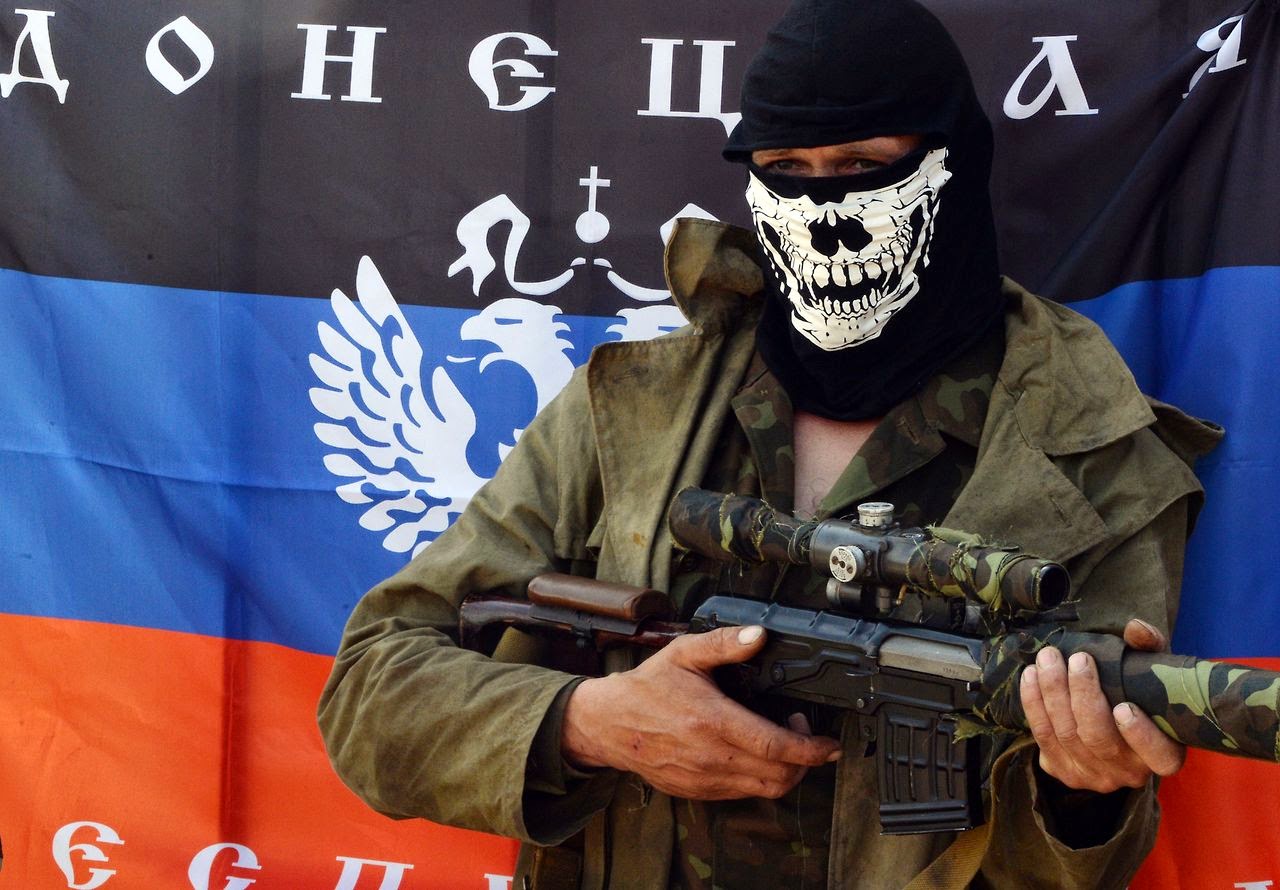 A member of the "DNR" unit of Russia's hybrid army in Ukraine in front of the unit's flag