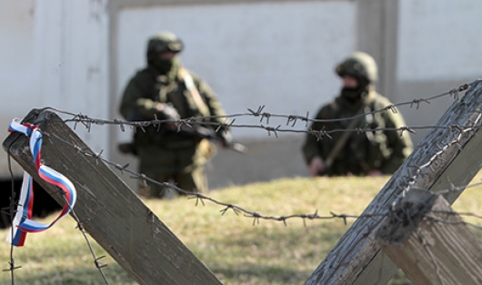 Russian soldiers behind a razor-wire barrier