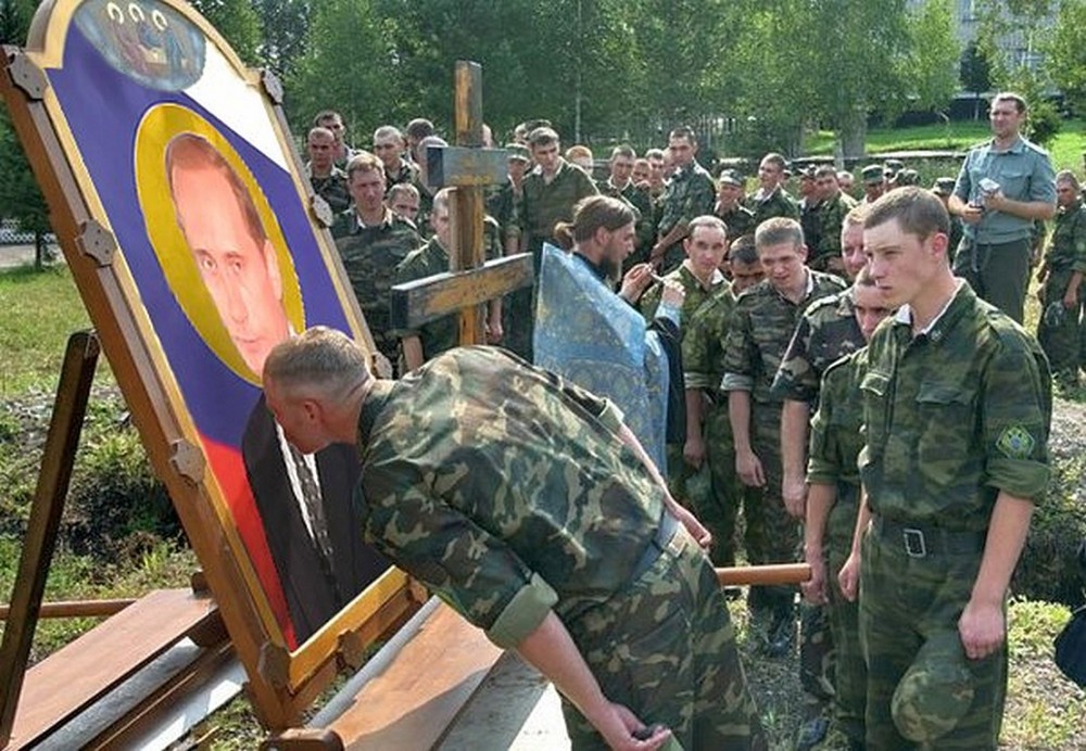 Russian soldiers line up to kiss an “icon” of Putin, while a Russian Orthodox priest of the Moscow Patriarchate blesses them. (Image: Social media)