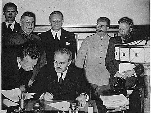 Beaming Stalin supervising the signing of the so-called Molotov-Ribbentrop Pact dividing Poland between Hitler's regime and his own, Aug 23, 1939. From left to right: Richard Schulze-Kossens, Waffen-SS officer; Boris Shaposhnikov, Chief of the General Staff of the Red Army; Alexey Shkvarzev, Soviet Ambassador in Germany; Joachim von Ribbentrop, German Minister of Foreign Affairs; Vyacheslav Molotov, Soviet Minister of Foreign Affairs (sitting); Joseph Stalin, Soviet dictator; Vladimir Pavlov, First Secretary of the Soviet embassy in Germany (Image: TASS)
