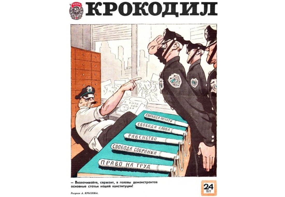 The cover caricature from a 1977 issue of the Soviet satirical propaganda journal "Krokodil": "Sergeant, hammer into the heads of the demonstrators the main articles of our constitution." (The police batons on the desk are named: freedom of the press, freedom of speech, equality, freedom of assembly, right to work.) Author: A. Krylov