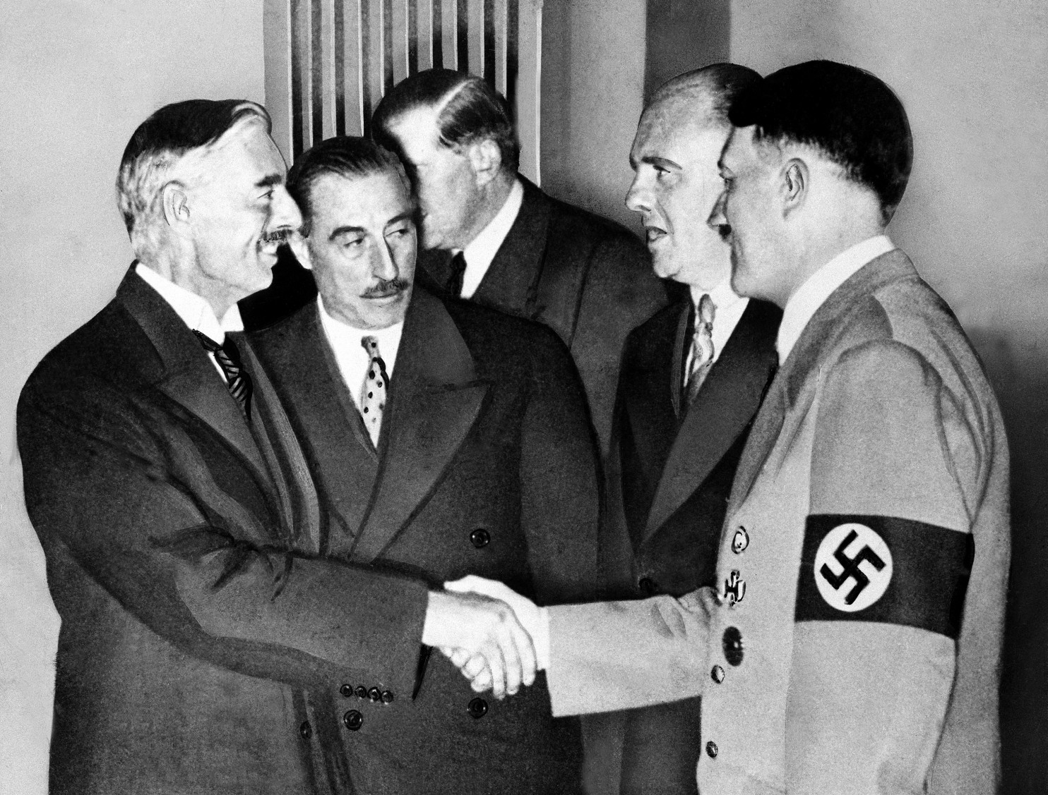 Hands clasped in friendship, Adolf Hitler and England's Prime Minister Neville Chamberlain, are shown in this historic pose at Munich on Sept. 30, 1938. This was the day when the premier of France and England signed the Munich agreement, sealing the fate of Czechoslovakia. Next to Chamberlain is Sir Neville Henderson, British Ambassador to Germany. Paul Schmidt, an interpreter, stands next to Hitler. (Image: AP)