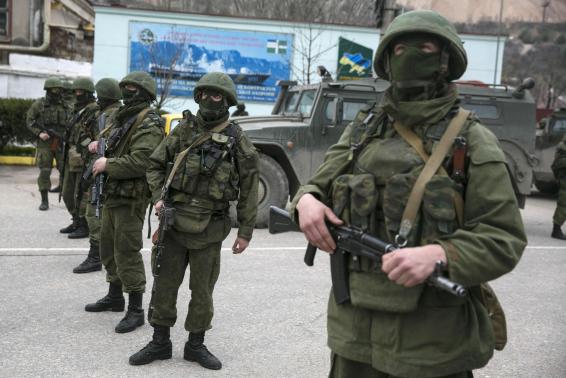 Masked Russian servicemen stand near their army vehicles blockading a Ukrainian border guard base in the Crimean town of Balaclava. March 2014