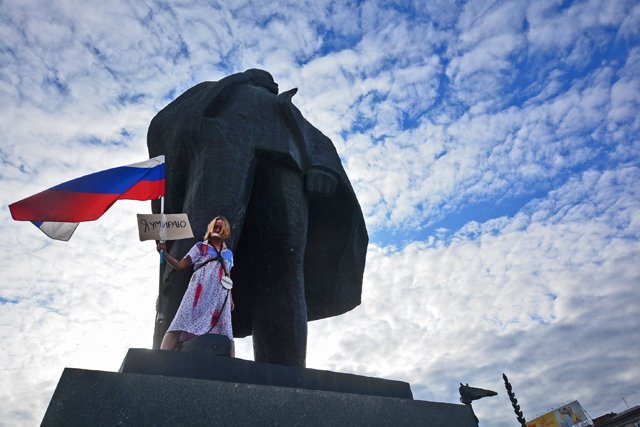 Dressed as Russia in a blood-stained outfit and holding a national flag, a woman chained herself to a Lenin statue in Novosibirsk, Russia to protest deteriorating human rights and increasing poverty. The large sign attached to the flag says: "I Am Dying." Three smaller signs hanging off the chain crisscrossing her body say: "Police," "Fear" and "Censorship." August 22, 2017 (Photo: Alyona Martynova / Sib.fm)