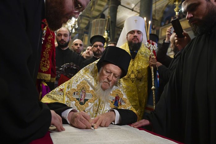 Ecumenical Patriarch Bartholomew signing the tomos of autocephaly of the Orthodox Church of Ukraine on January 5, 2019. Metropolitan Epiphanius of Ukraine stands behind him. (Photo: Wikimedia Commons)