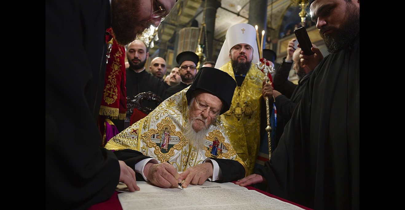 Universal Patriarch Bartholomew signing the tomos of autocephaly of the Orthodox Church of Ukraine on January 5, 2019. Metropolitan Epiphanius of Ukraine stands behind him. (Photo: Wikimedia Commons)