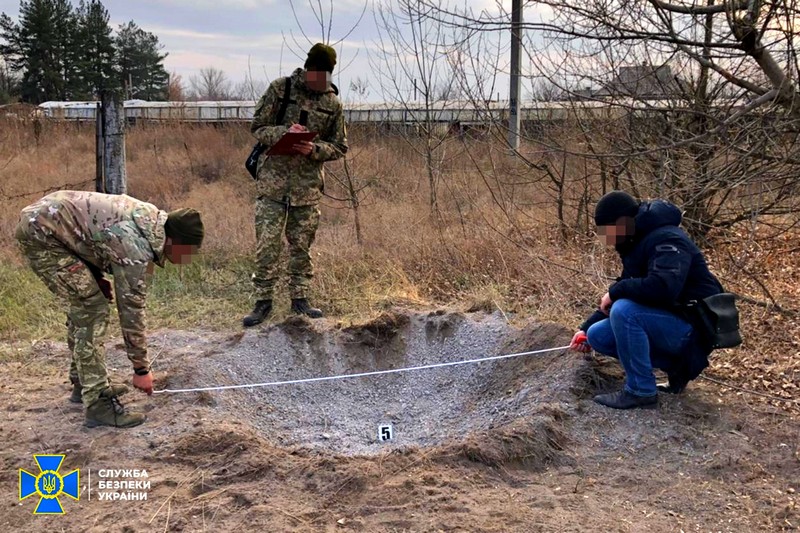 SBU operative inspecting a crater left behind by an explosion in the Donbas war zone. Photo: Security Service of Ukraine ~