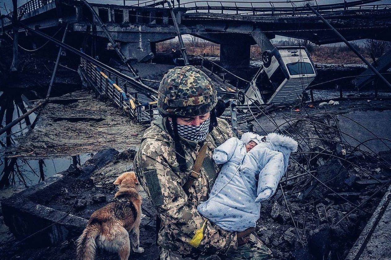 Ukrainian defender carries a baby over a river using the remains of a bridge destroyed by Russian bombardment in an area of continued Russian attacks. March 4, 2022. The Russo-Ukrainian War (2014-present). Credit: Ukrainian Freedom