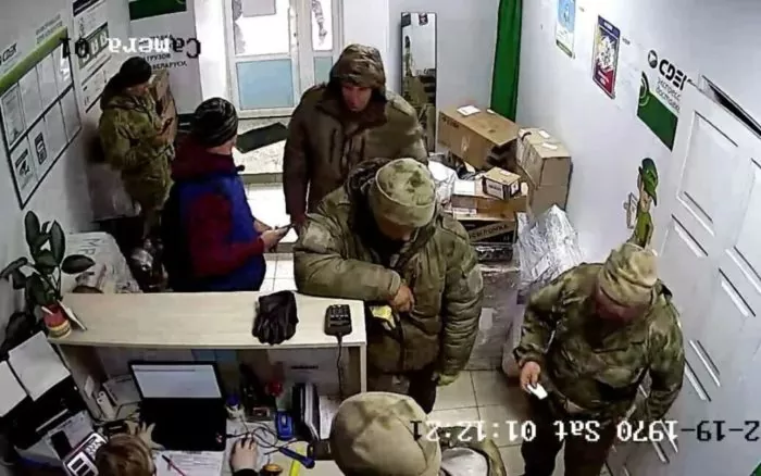 Screenshot from a CCTV camera shows Russian soldiers at a Belarusian service centre sending stolen goods from Ukraine to their homes in the Russian Federation. ~