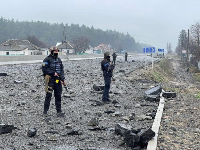Police officers inspect a road to Bohdanikva destroyed by Russian tanks.