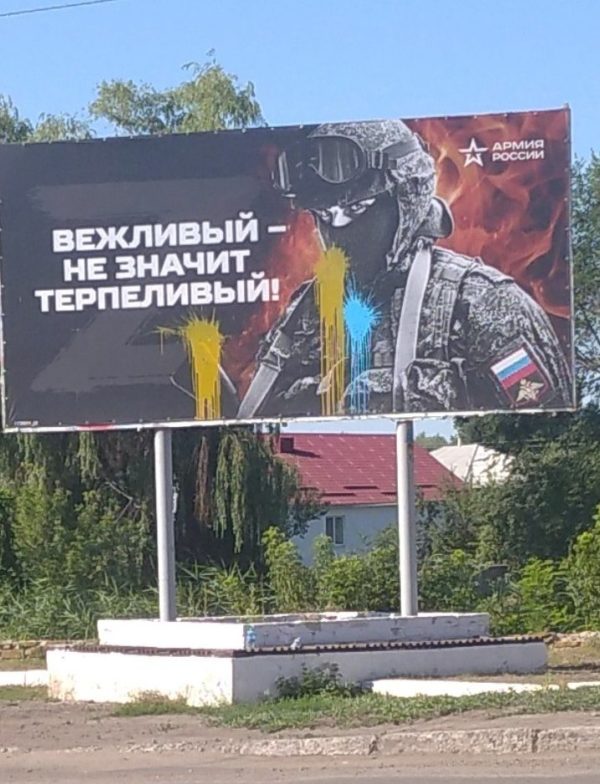 Russian military propaganda billboard reading “Polite doesn’t mean patient” vandalized with paint in Ukrainian colors. Occupied Svatove, July 2022. Source. ~