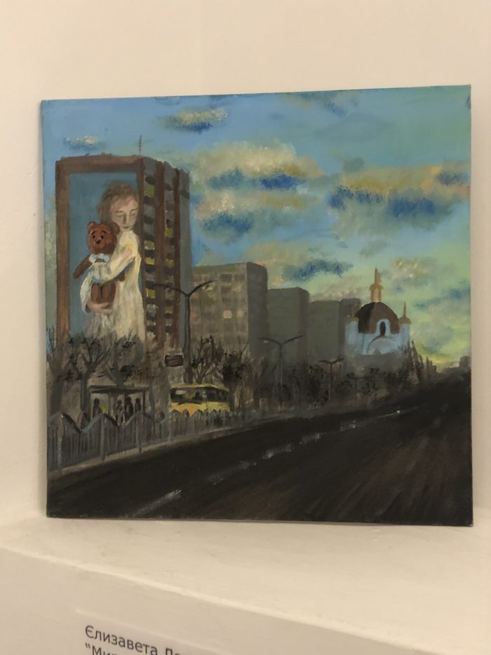 “Peaceful sky” by Yelyzaveta Lapteva. The painting also shows the mural in Mariupol which showed Milana — a girl who was a victim of Russian shelling in 2015. Russians painted the mural over after occupying the city. ~