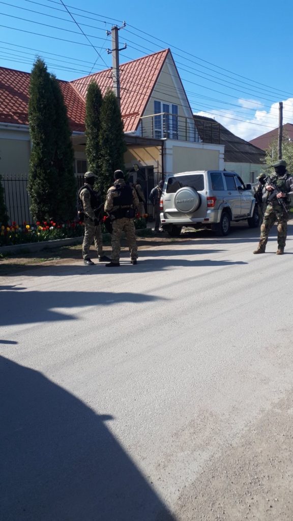 The image shows FSB officers standing next to the house of Crimean Tatar activist Abdureshit Dzhepparov. Source: Crimean Solidarity